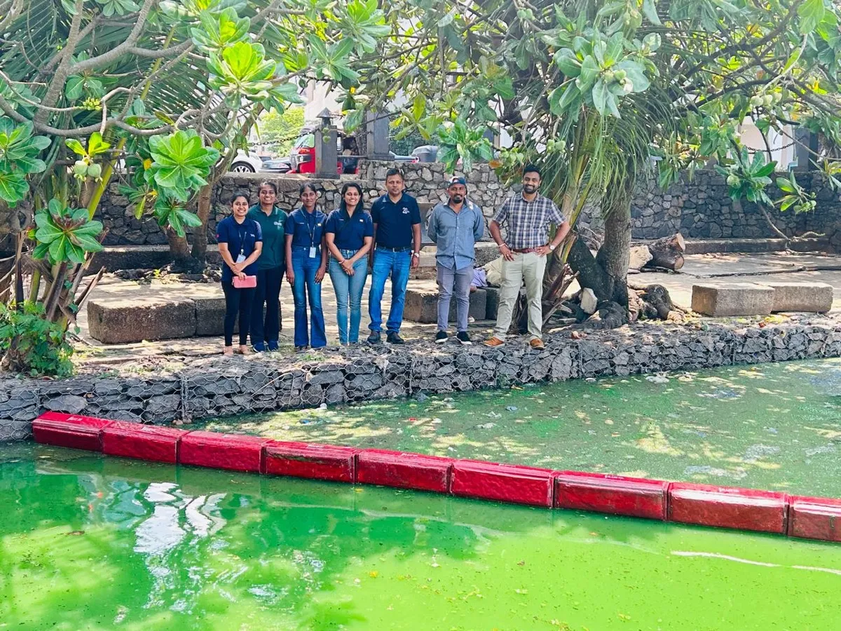 An MAS Silueta team beside an inland waterway with a red floating Ocean Strainer barrier in the green water